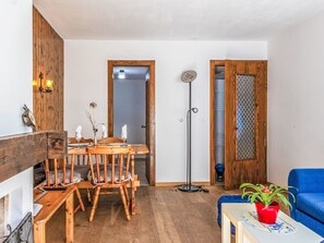 Ein Essbereich mit Holztisch und -stühlen, einer stehenden Stehlampe und einem blauen Sofa.