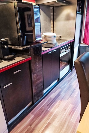 Una cocina moderna con una encimera negra, una cafetera y una pila de platos.