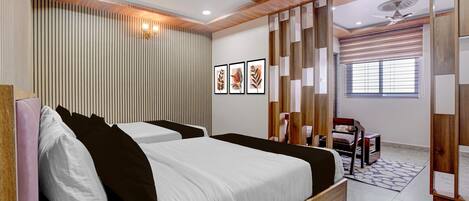 A bedroom with two beds, a ceiling fan, a window with blinds, and a decorative wall panel.