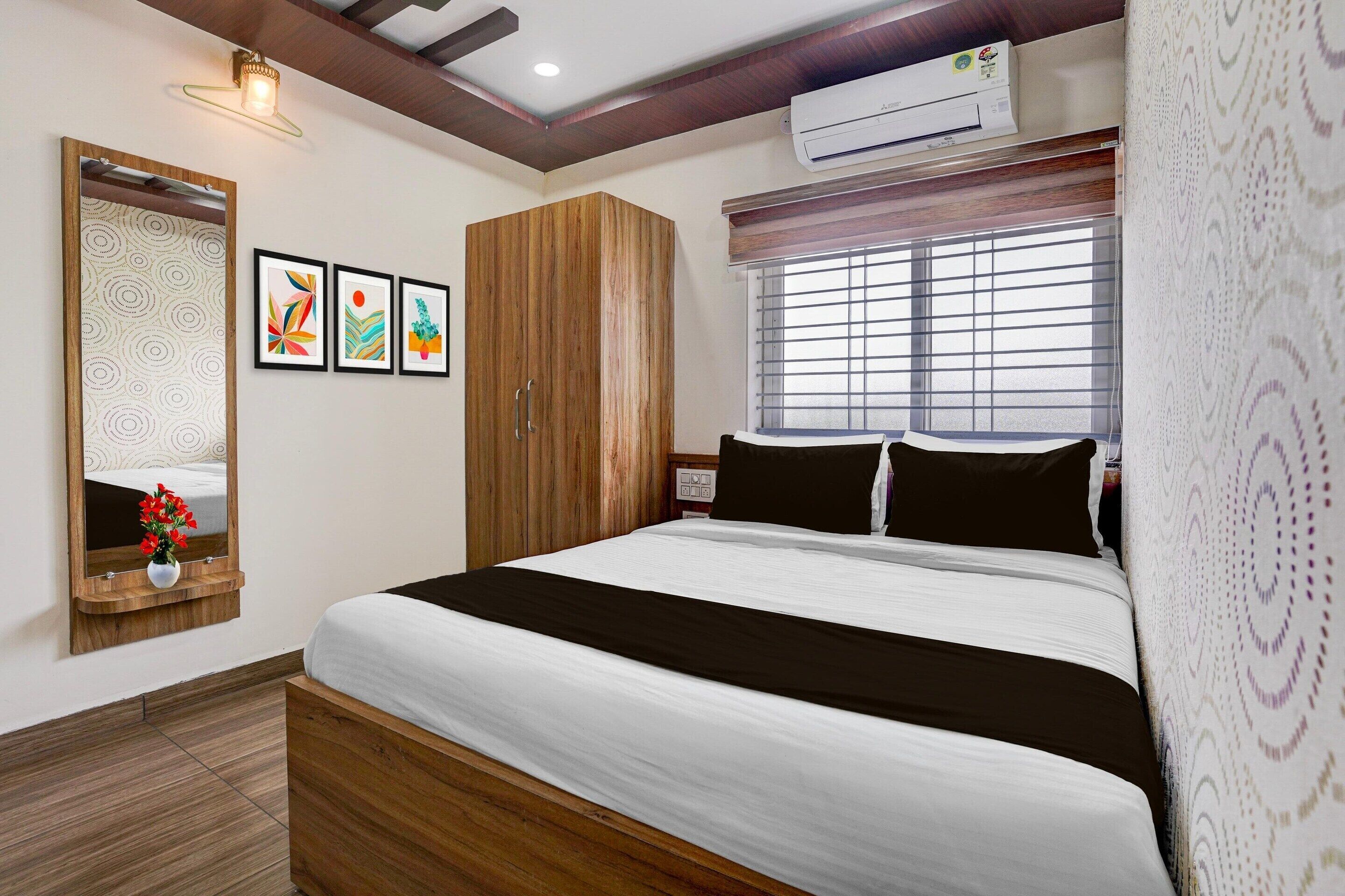 A bedroom with a bed, a wardrobe, a mirror, and framed artwork on the wall.