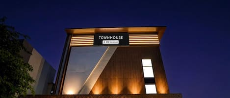 A modern townhouse with a large glass facade, a sign indicating OYO service, and a covered entrance.