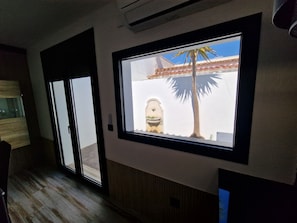 Um quarto com uma grande janela, uma porta e um aparelho de ar condicionado fixado na parede.