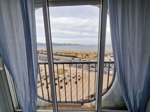 Ein Balkon mit Blick auf einen Strand, einen Parkplatz und ferne Berge.