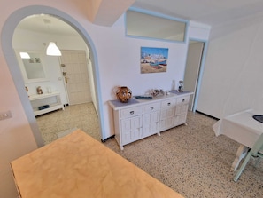 A room with a white cabinet, a painting, and a mirror. - KARINA APARTMENT BEACH-6 (Empuriabrava)