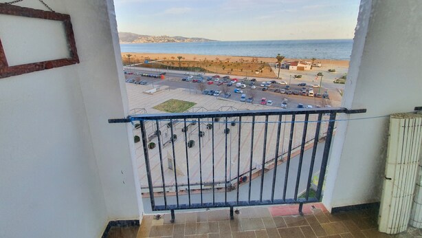 Een balkon met uitzicht op een parkeerplaats en een strand.