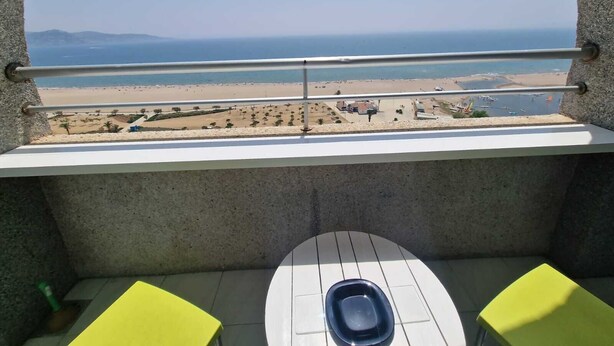 A balcony with a view of a beach, a toilet, and two yellow chairs. - APARTMENT YELLOW SEA 173 (Empuriabrava)