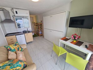 A compact living space with a kitchenette, a sofa, a TV, and a small dining area. - APARTMENT YELLOW SEA 173 (Empuriabrava)