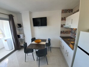 A modern kitchen with a flat-screen TV, a dining table with chairs, and a refrigerator. - APARTMENT BRUEL 17-12. (Empuriabrava)