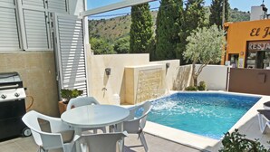 A backyard with a swimming pool, a barbecue grill, and outdoor seating.