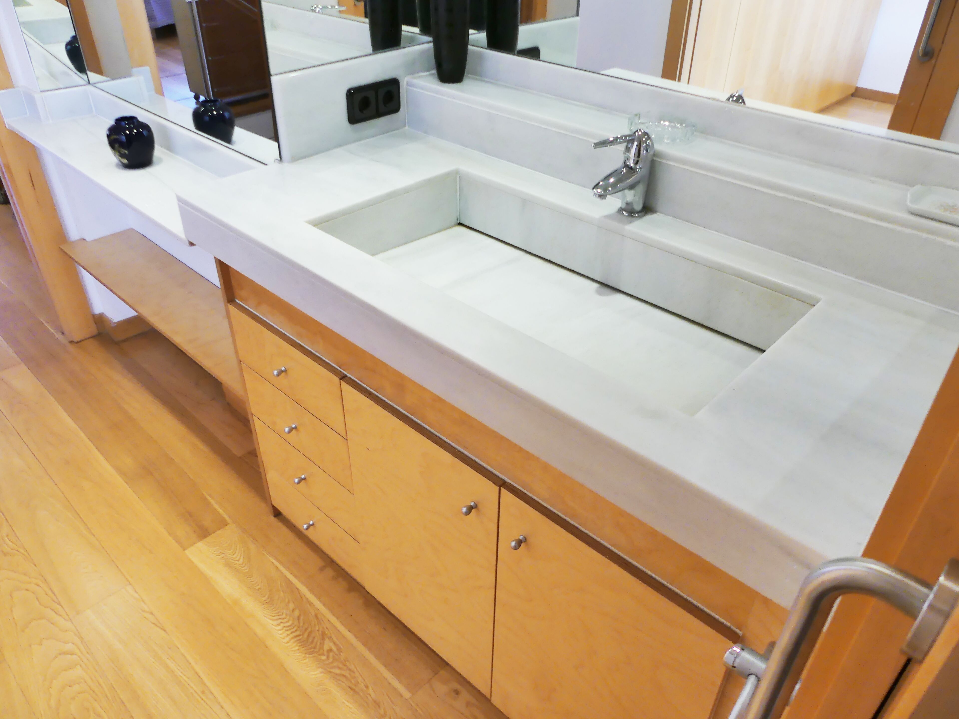 A bathroom with a double sink, wooden cabinets, and a mirror.