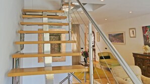 A modern staircase with wooden steps and metal railings, leading to a landing with a light fixture.