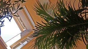 A view of a building's interior with a balcony and a plant in the foreground.