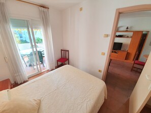 Une chambre à coucher avec un lit, une chaise, un bureau et un téléviseur.