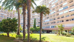 A multi-story hotel with a courtyard featuring palm trees and a grassy area. - GRISLAND POOL STUDIO (Roses)