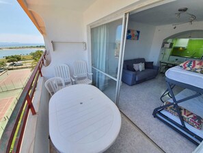 Un balcon avec une table et des chaises, un canapé, un lit et une vue sur la mer.