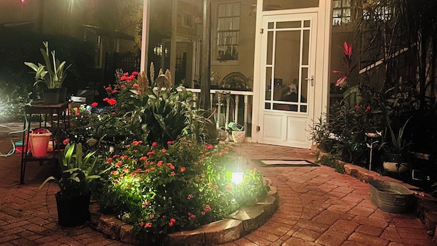 A building with a covered entrance, potted plants, and outdoor lighting.