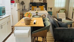 A compact living space with a kitchenette, a dining area, and a seating area with a sofa and chairs.