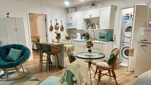 A modern kitchen with white cabinets, a microwave, and a washing machine.