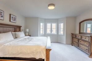 A bedroom with a large bed, a dresser, a nightstand, and a window with a view. - Modern Oakville Home | 2 King, 2 Queen + Gazebo (Oakville)