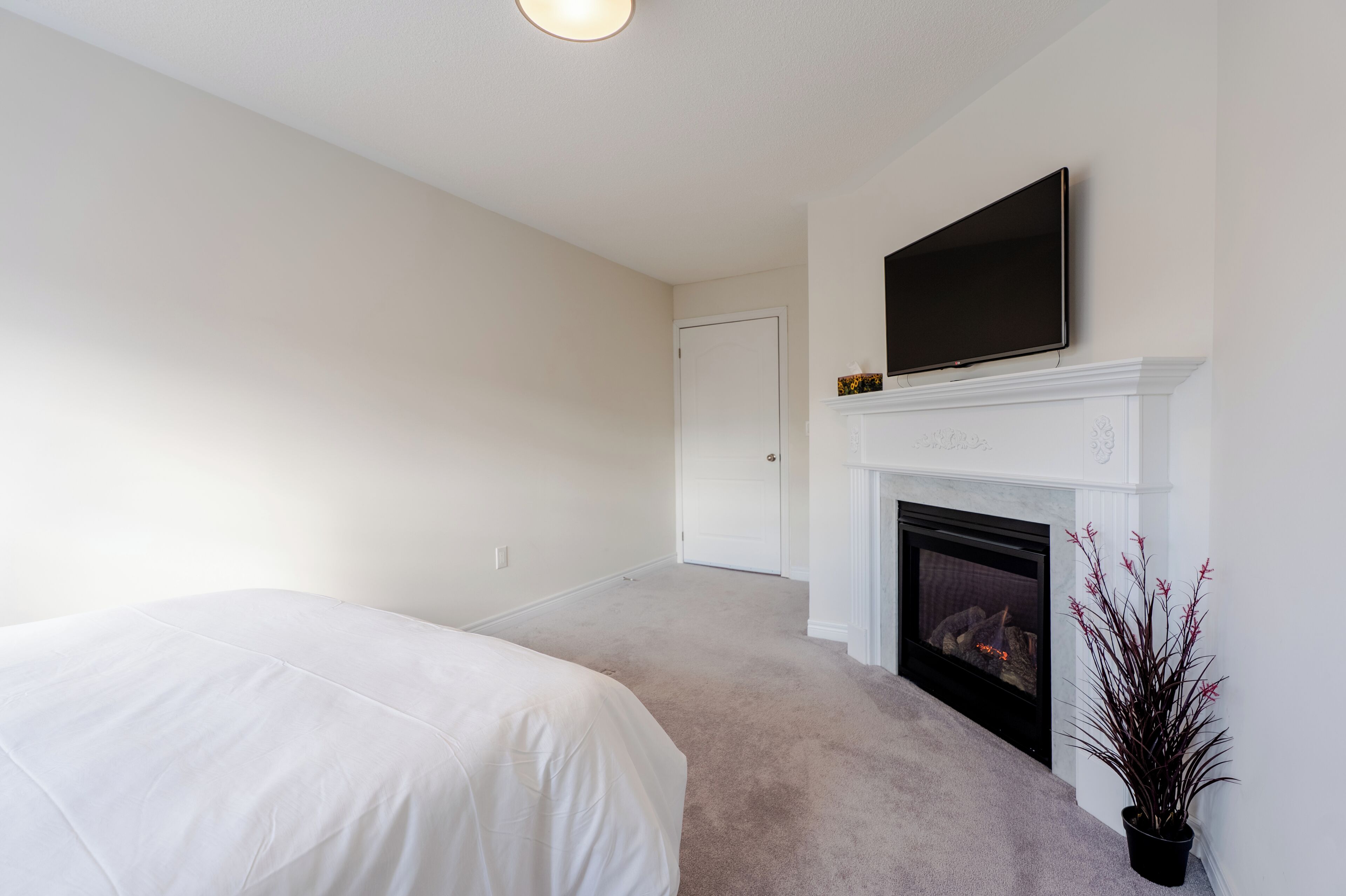 Ein Schlafzimmer mit Bett, Kamin, Fernseher und einer Tür.