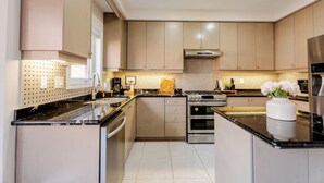 A modern kitchen with stainless steel appliances, a central island, and a dot-patterned backsplash. - Modern Oakville Home | 2 King, 2 Queen + Gazebo (Oakville)
