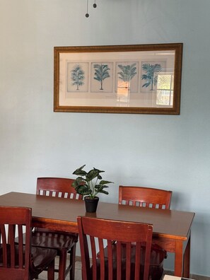 A dining area with a wooden table and chairs, a framed botanical print on the wall, and a potted plant on the table. - Peaceful 3-bedroom apartment with AC in charming Cataño (Cataño)