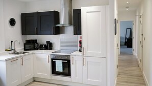 Une cuisine moderne avec des armoires blanches, des appareils électroménagers noirs et une hotte de cuisine en acier inoxydable.