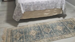 Een bed met een beddengoed met een patroon, een welkomstkussen en een passend kussen met een vogelprint.