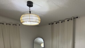 Un dormitorio con cama, cómoda de madera, espejo y lámpara colgante.