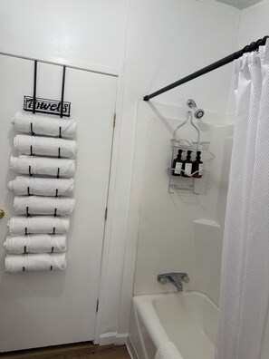 Ein Badezimmer mit Handtuchhalter, Dusche und einer kleinen Ablage für Pflegeprodukte.