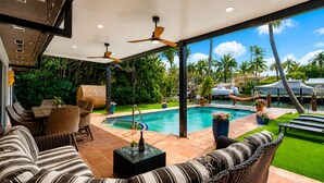 An outdoor patio with a pool, wicker furniture, and a view of the pool area. - Fox Isles Luxury Waterfront With Pool Near Beach (Fort Lauderdale)