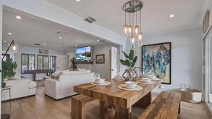 A spacious living area with a wooden dining table set for four, a white sofa, and a large painting on the wall. - Fox Isles Luxury Waterfront With Pool Near Beach (Fort Lauderdale)