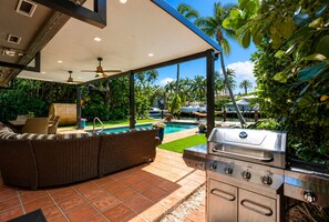 Eine Terrasse im Freien mit Grill, Sitzgelegenheiten und einem Pool.