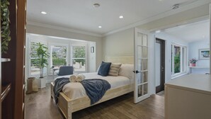 A bedroom with a bed, a window with blinds, a plant, and a door leading to another room. - Fox Isles Luxury Waterfront With Pool Near Beach (Fort Lauderdale)