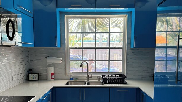 A modern kitchen with blue cabinets, a window, a sink, and a stove. - Family Friendly 8-bedroom house in Cataño, Up to 30+ Guests (Cataño)