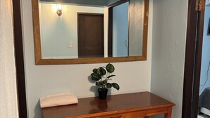 A wooden console table with a mirror above it, a potted plant, and a towel on the table. - Family Friendly 8-bedroom house in Cataño, Up to 30+ Guests (Cataño)