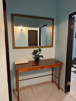 Une console en bois, avec un miroir au-dessus, une plante en pot et une serviette posée sur le plateau.