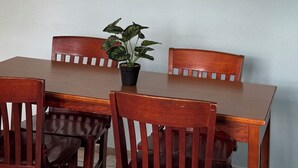 A dining area with a wooden table and chairs, a framed botanical print on the wall, and a potted plant on the table. - Family Friendly 8-bedroom house in Cataño, Up to 30+ Guests (Cataño)