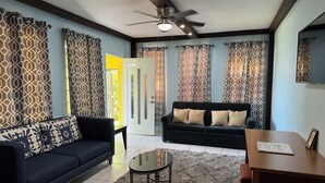 A living room with a sofa, a coffee table, and a TV. - Family Friendly 8-bedroom house in Cataño, Up to 30+ Guests (Cataño)