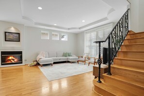 A living room with a fireplace, a sofa, a coffee table, and a staircase with a railing. - Toluca Lake Townhome, Central to Hollywood attractions (Los Angeles)