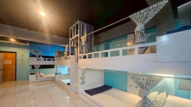 A multi-level bunk bed room with a ladder, a small seating area, and a window. - New Me U Hostel (Chiang Mai)