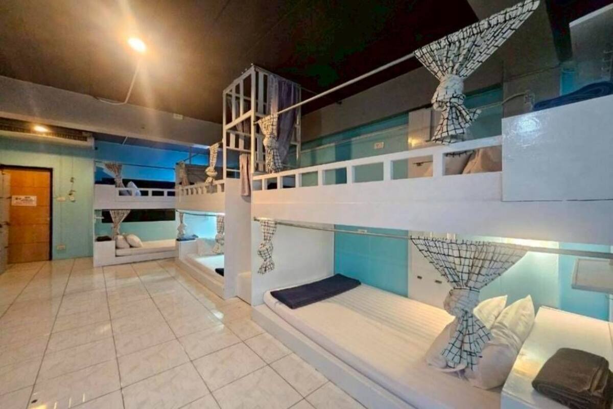 Quarto com beliche de vários níveis, uma escada, um pequeno espaço para sentar e uma janela.
