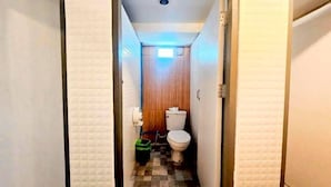 A narrow hallway leading to a bathroom with a toilet, a small window, and a ceiling light. - New Me U Hostel (Chiang Mai)