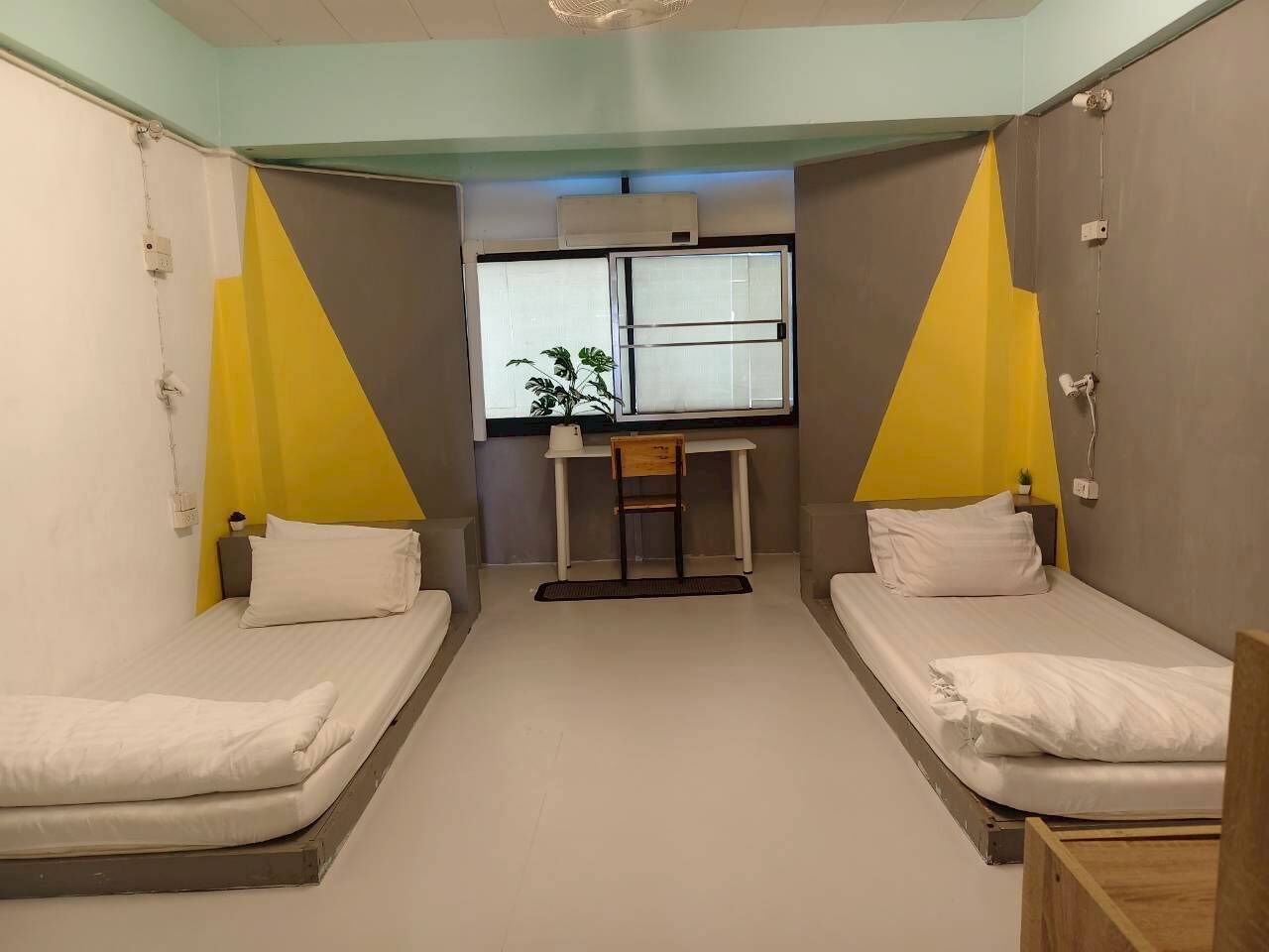 Ein Zimmer mit zwei Betten, einem Schreibtisch und einem Fenster.