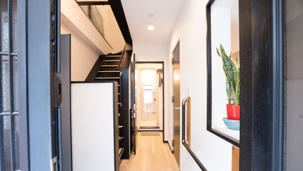 Un passadís modern amb una escala, una planta en test i una porta.