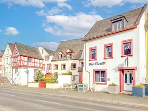 Eine Reihe traditioneller europäischer Gebäude, rechts ein Schild mit der Aufschrift 'Die Quelle'.