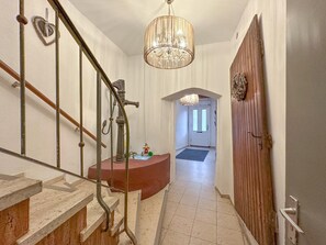 Eine Treppe mit Metallgeländer, einer Kristallleuchtre und einer Holztür.