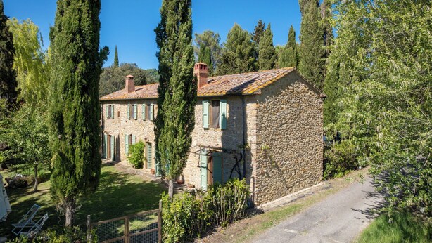 A stone house with a tiled roof, surrounded by tall trees and a clear sky. - Il Salice by Interhome (Montescudaio)