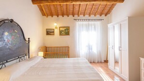 Ein Schlafzimmer mit Holzboden, einem Bett, einem Nachttisch, einem Kleiderschrank und zwei gerahmten Bildern an der Wand.