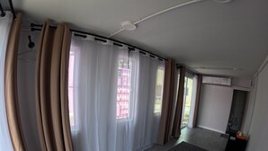 Una habitación con cama, cortinas y ventana.